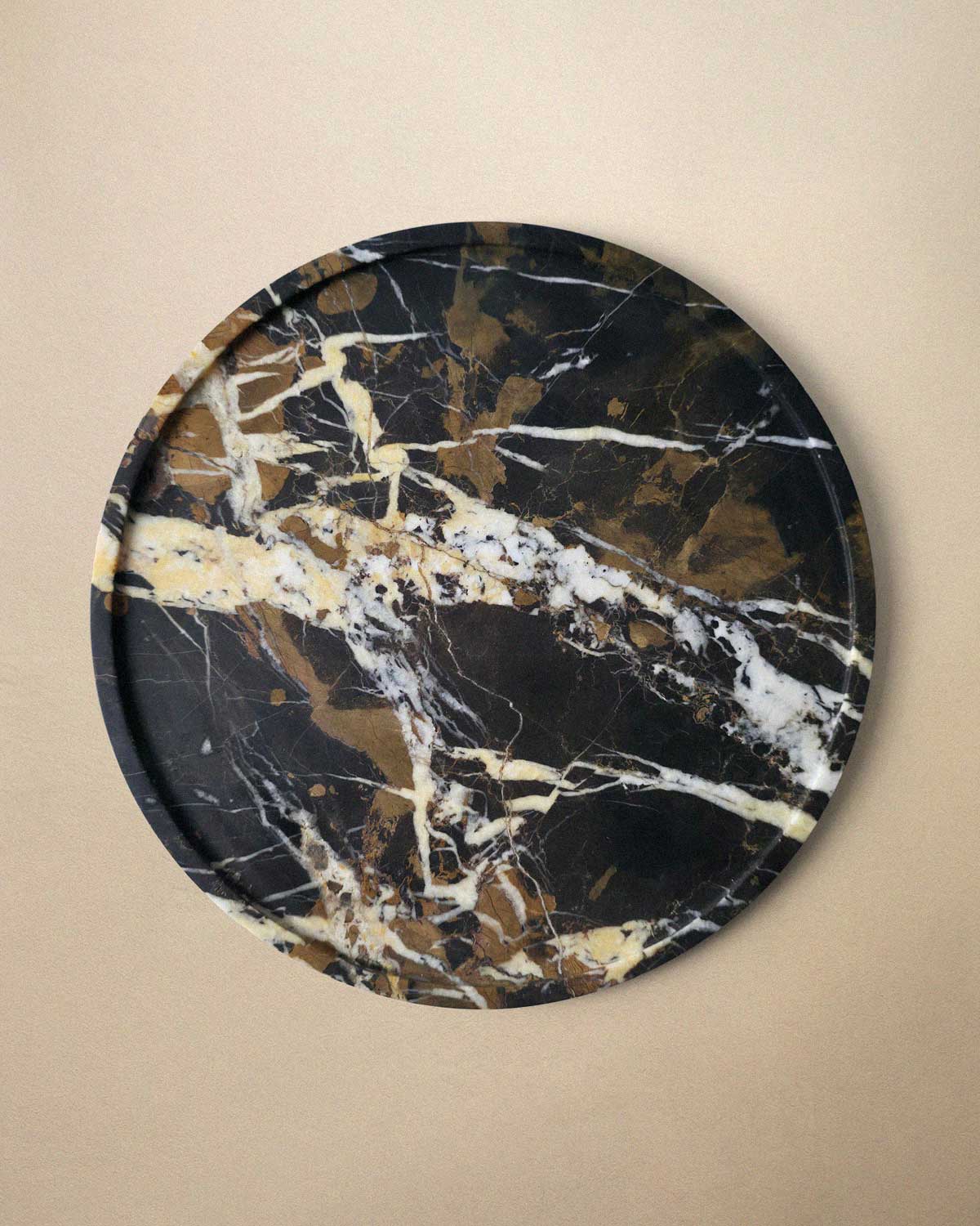 Round black marble decorative tray on a beige background