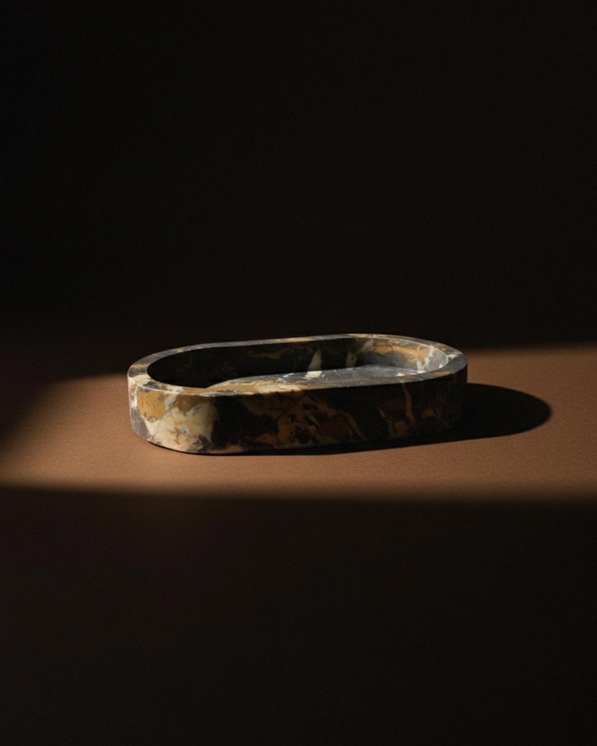 Black marble oval bathroom tray on a beige background