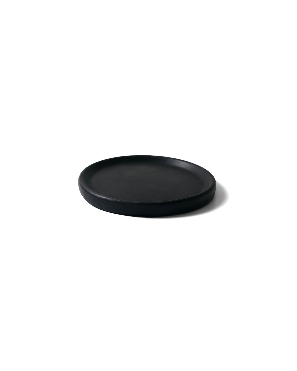 Side-angle photo of Oaxacan black clay appetizer plate showing raised rim and matte finish.