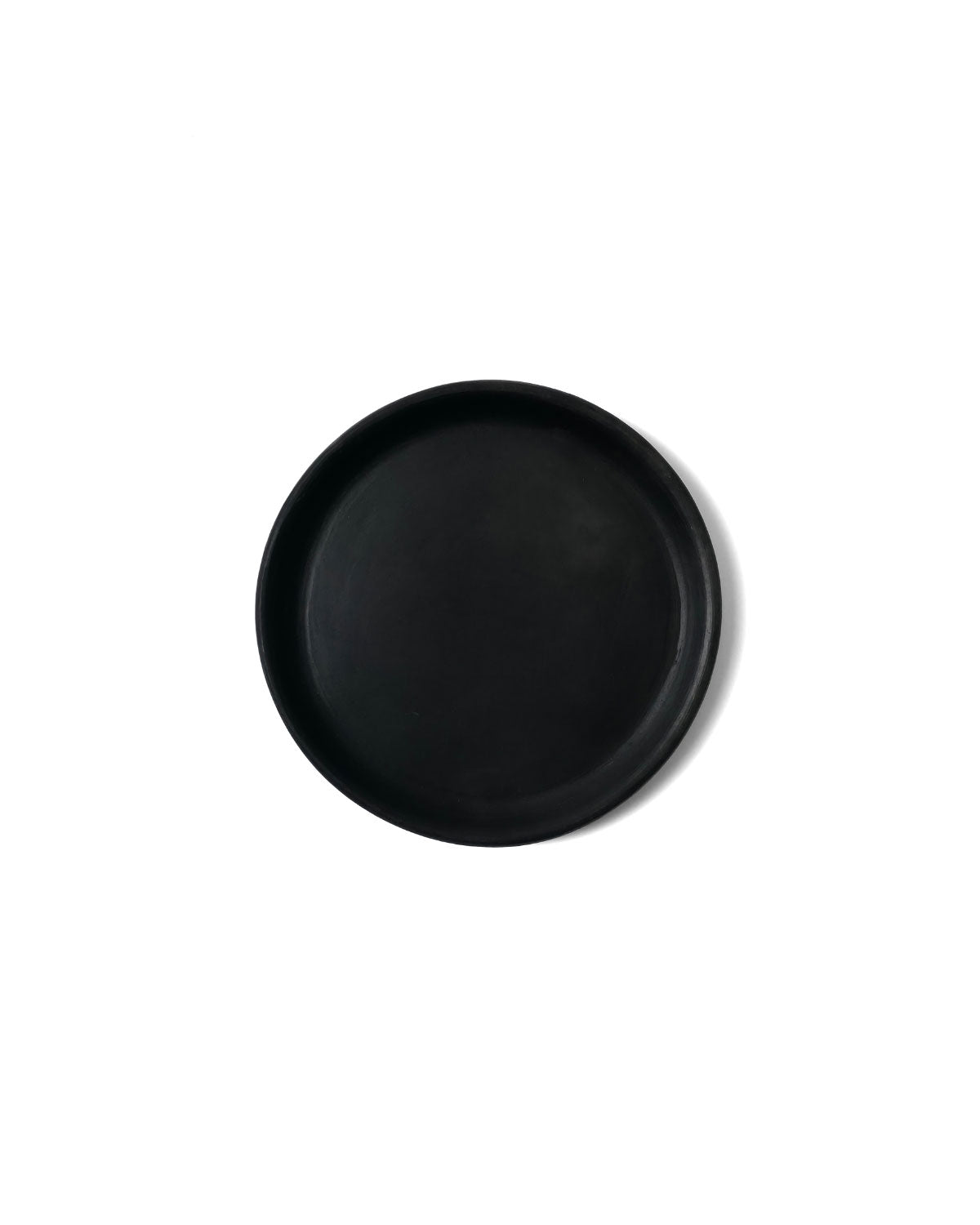 Top-view of matte Oaxacan black appetizer plate on white studio backdrop.
