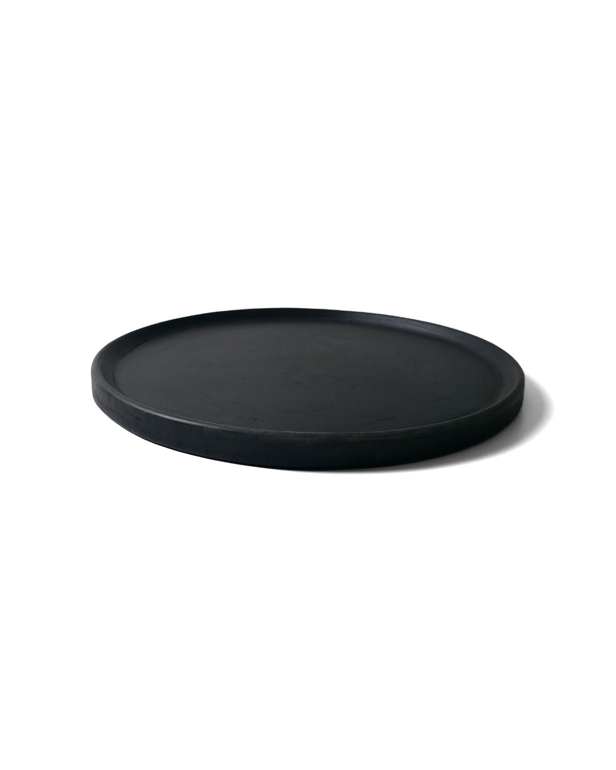Side-angle photo of Oaxacan black dinner plate showing low rim and matte finish.