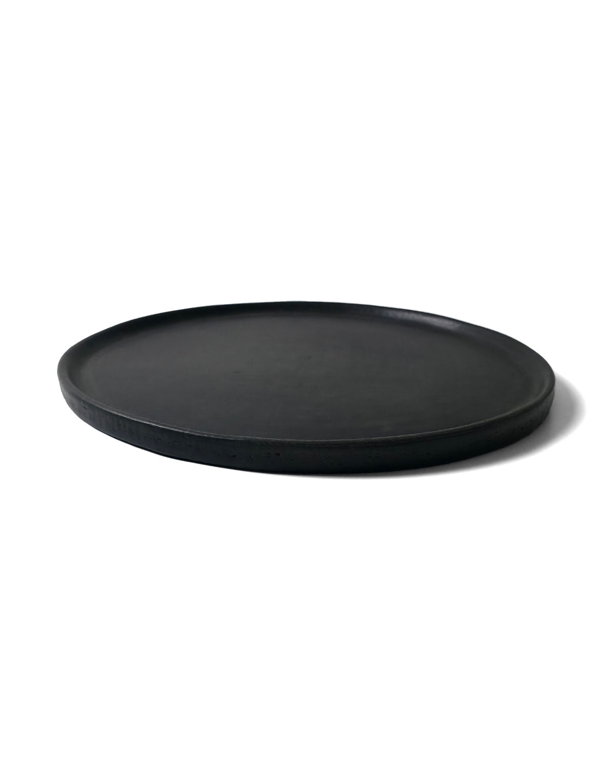 Side-angle photo of Oaxacan black serving platter showing low rim and velvety matte finish.