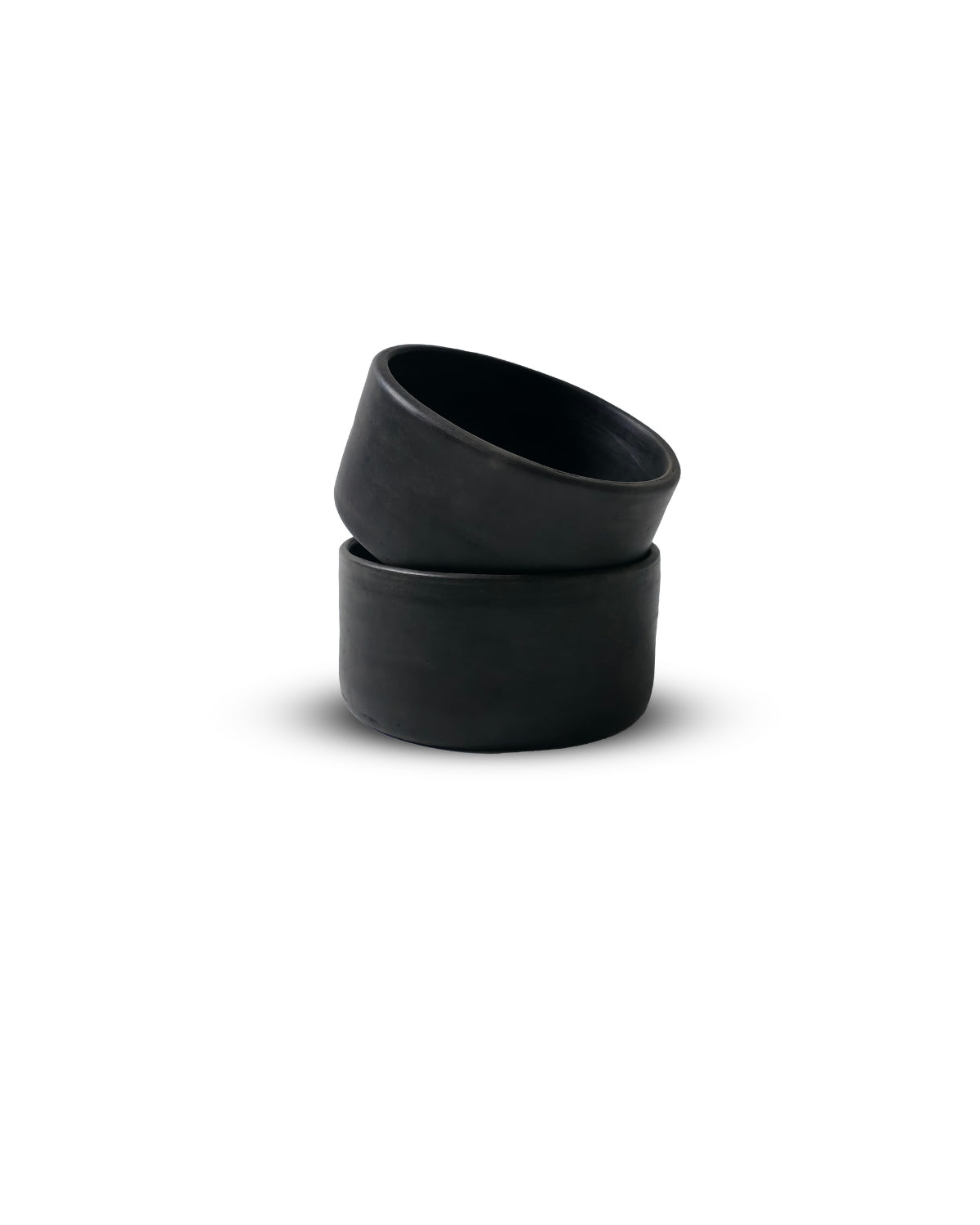 Two matte Oaxacan black clay salsa bowls stacked at an angle, highlighting artisanal texture.