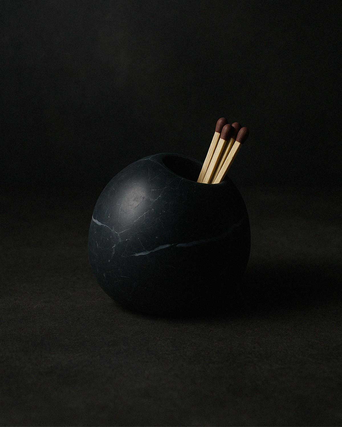 Nero Marquina marble match holder styled with matchsticks in a moody setting