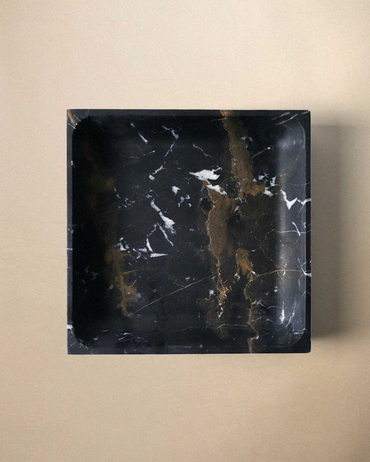 Black marble square tray on a beige background