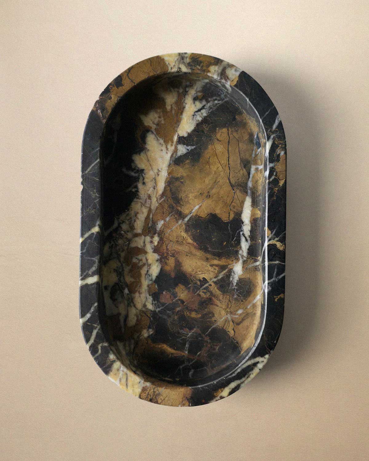 Black marble oval bathroom tray on a beige background