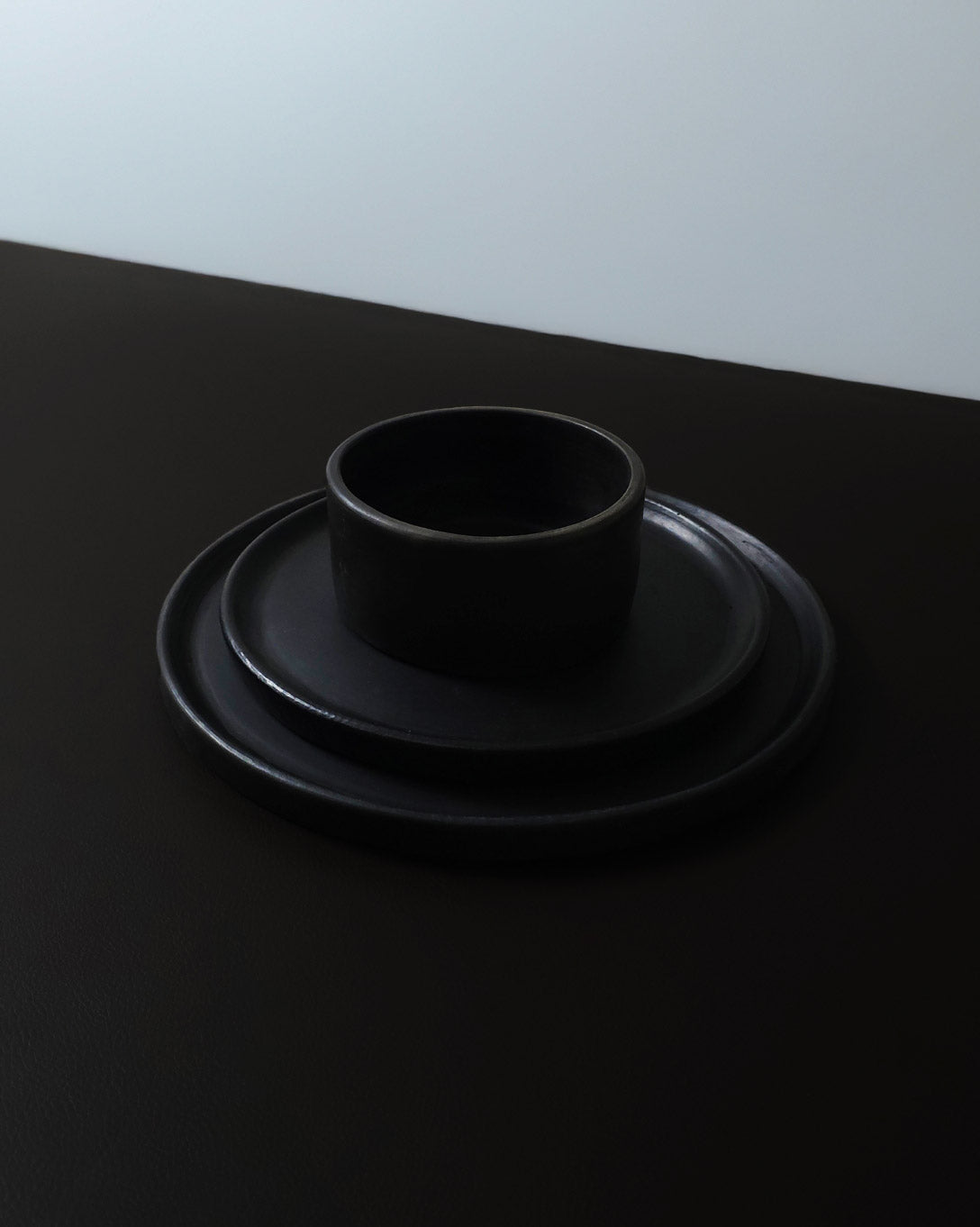 Oaxacan black clay salsa bowl stacked on matching black appetizer and dinner plates.