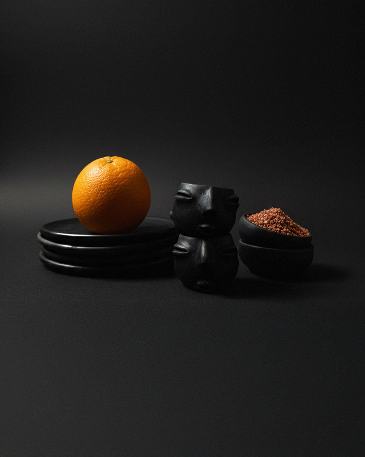 Stacked Oaxacan black clay cups used as pinch bowls, with the top bowl holding a mound of reddish-brown mezcal worm salt.