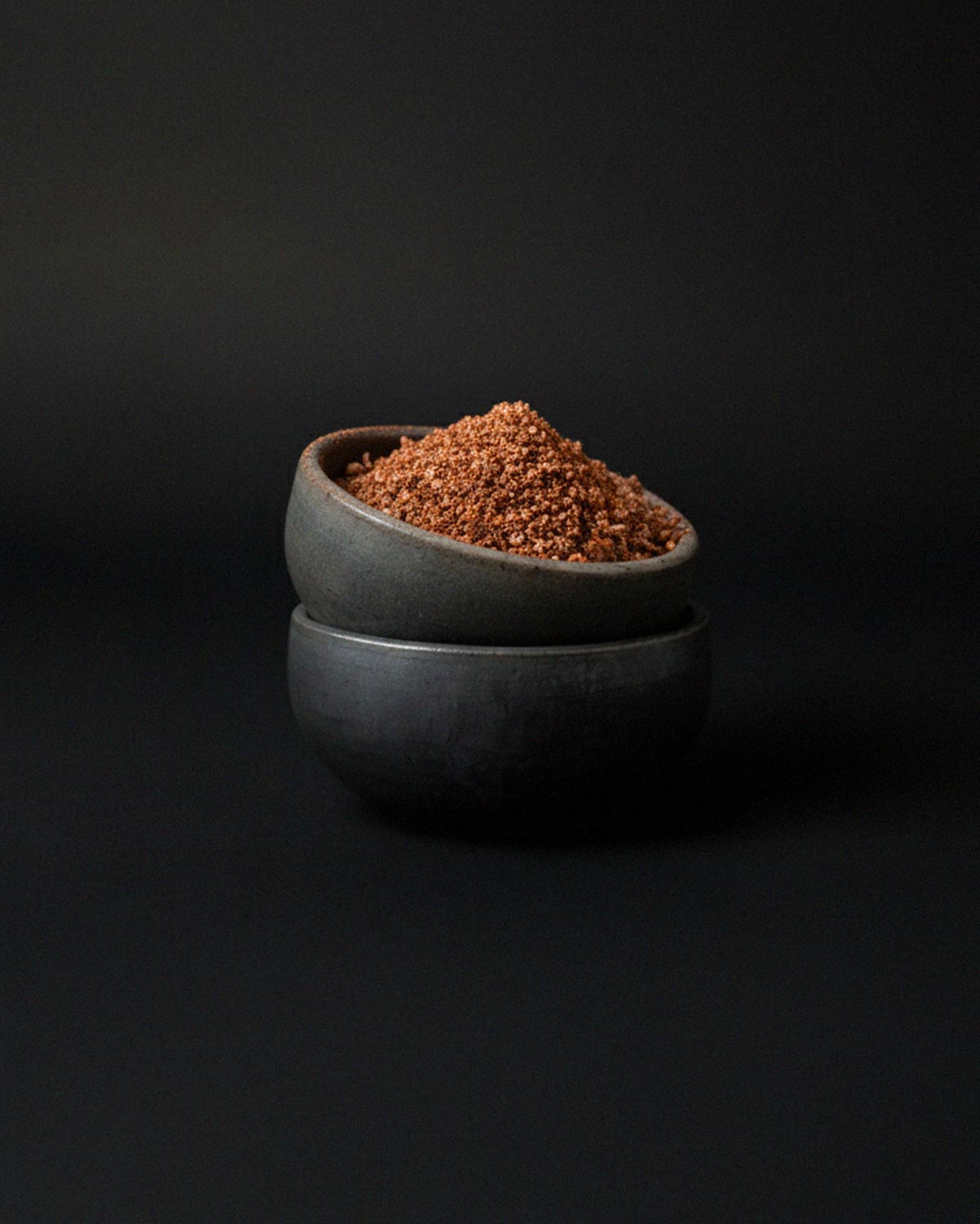 A pair of stacked Oaxacan clay pinch bowls, the top one filled with a mound of coarse mezcal salt.