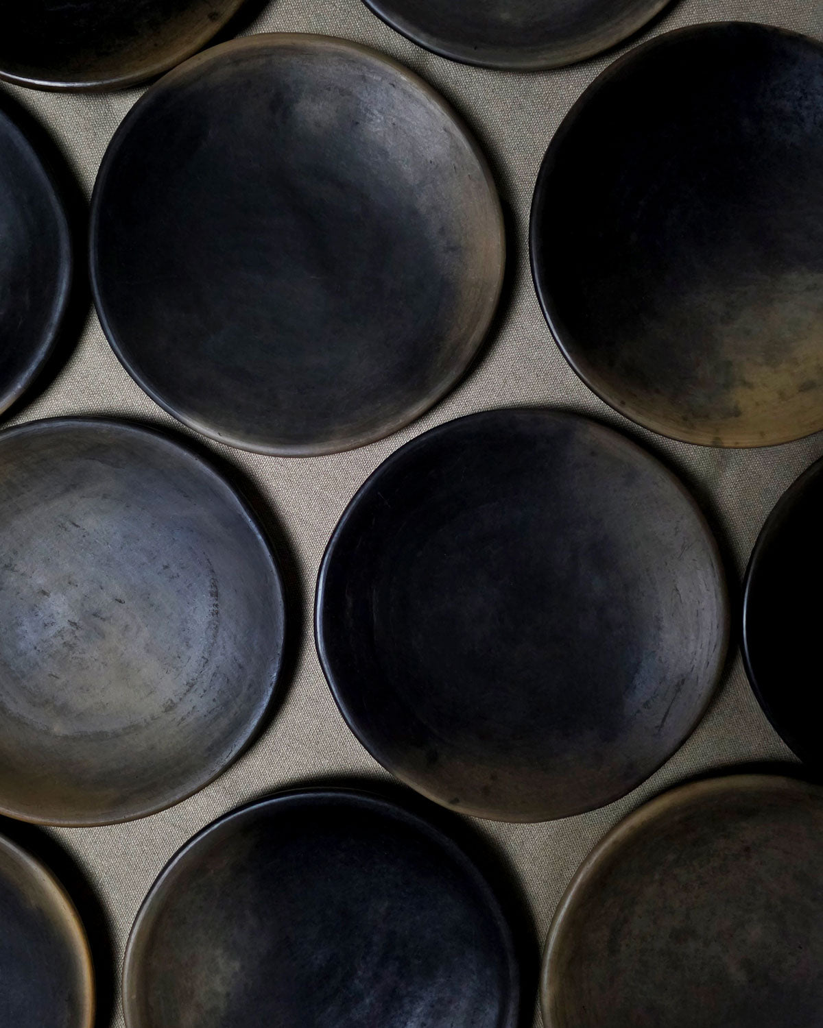 Top view of multiple handmade Oaxacan plates showing natural smoke-fired variations.